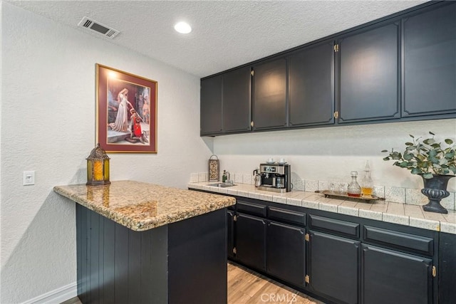 9292 Garden St, Rancho Cucamonga, CA 91701 - indoor wet bar featuring a textured ceiling, light wood-style floors, a textured wall, and recessed lighting