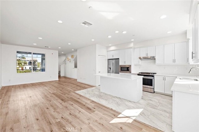 284 Novel, Irvine, CA 92618 - kitchen with appliances with stainless steel finishes, under cabinet range hood, a kitchen island, backsplash, and light countertops