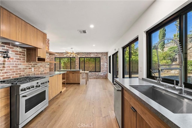 22526 Napa St, West Hills, CA 91304 - kitchen with stainless steel appliances, brick wall, modern cabinets, light wood finished floors, and plenty of natural light