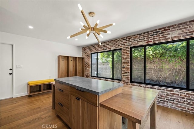 22526 Napa St, West Hills, CA 91304 - kitchen with wood-type flooring, brick wall, a ceiling fan, dark countertops, and a center island