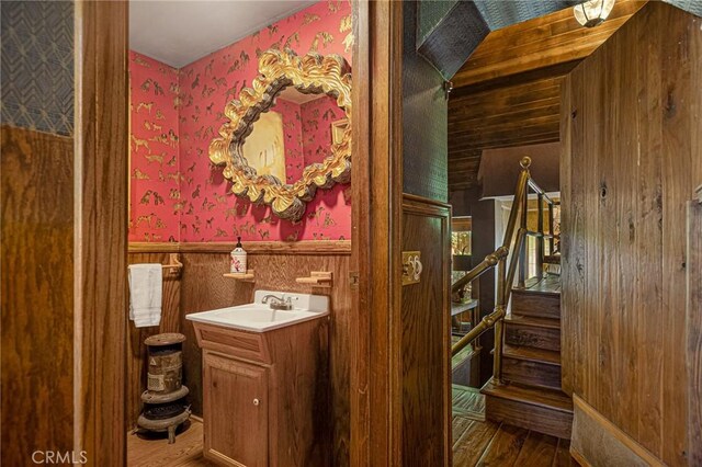 969 Oak Dr, Crestline, CA 92325 - bathroom featuring wallpapered walls, wood finished floors, a wainscoted wall, vanity, and wood walls