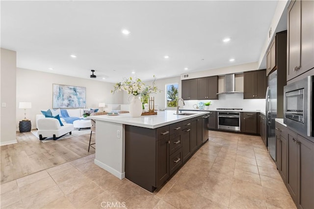 107 Bowery, Irvine, CA 92612 - kitchen featuring wall chimney exhaust hood, stainless steel appliances, open floor plan, a kitchen island with sink, and light countertops