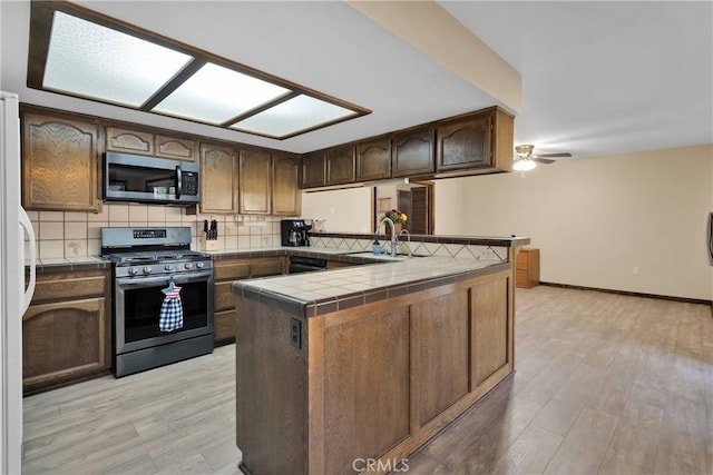 7505 Jenkins Ave, Hesperia, CA 92345 - kitchen with stainless steel appliances, tile counters, decorative backsplash, and light wood finished floors