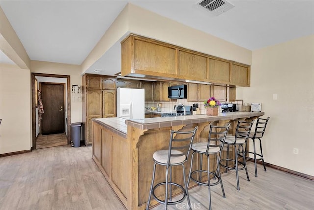 7505 Jenkins Ave, Hesperia, CA 92345 - kitchen featuring white refrigerator with ice dispenser, black microwave, tile countertops, a peninsula, and light wood finished floors