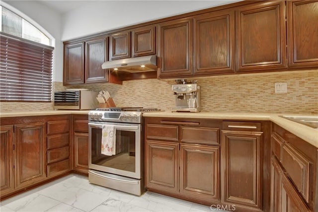 1629 E Palm Ave Unit 3, El Segundo, CA 90245 - kitchen with stainless steel gas stove, under cabinet range hood, light marble finish flooring, light countertops, and backsplash