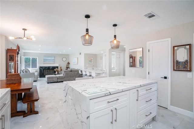 2741 Olympic View Dr, Chino Hills, CA 91709 - kitchen with white cabinets, decorative light fixtures, light stone countertops, a center island, and a premium fireplace