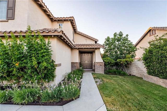 20642 Iris Canyon Rd, Riverside, CA 92508 - view of exterior entry with a lawn, brick siding, stucco siding, and a tiled roof