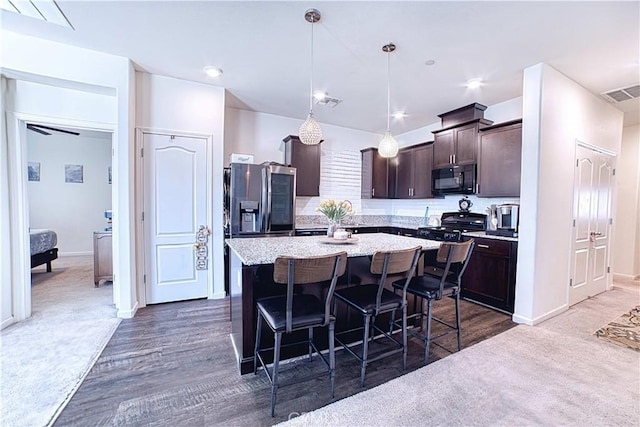 4262 Theresa Ln, Merced, CA 95348 - kitchen featuring black microwave, dark brown cabinetry, a kitchen breakfast bar, dark colored carpet, and a kitchen island
