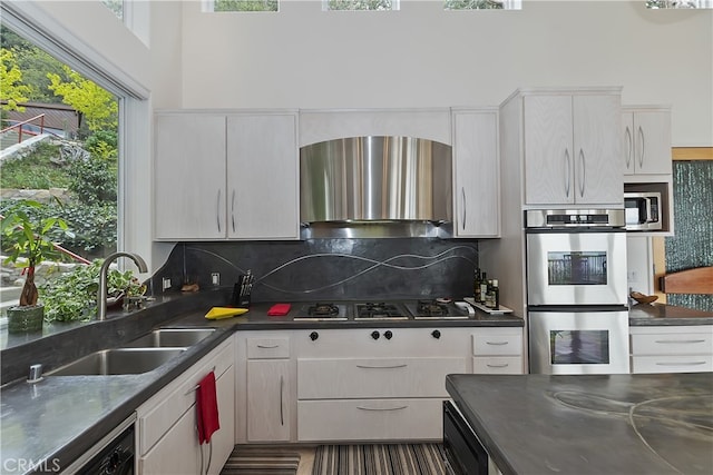 28527 Willow Rd, Lake Arrowhead, CA 92385 - kitchen featuring appliances with stainless steel finishes, wall chimney exhaust hood, backsplash, and white cabinetry