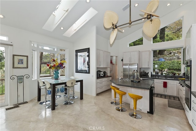 28527 Willow Rd, Lake Arrowhead, CA 92385 - kitchen featuring high end refrigerator, plenty of natural light, dark countertops, high vaulted ceiling, and a kitchen bar