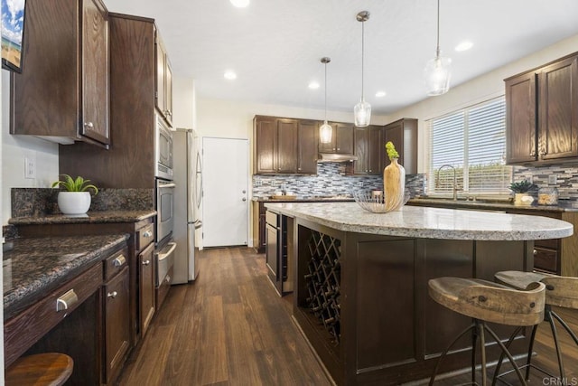 737 W Bel Esprit Cir, San Marcos, CA 92069 - kitchen with dark wood-type flooring, a kitchen island, a kitchen bar, backsplash, and recessed lighting