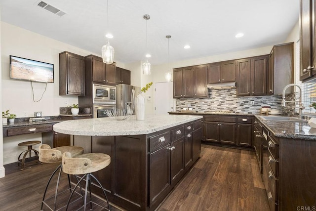 737 W Bel Esprit Cir, San Marcos, CA 92069 - kitchen with appliances with stainless steel finishes, dark wood finished floors, dark brown cabinets, a kitchen island, and recessed lighting