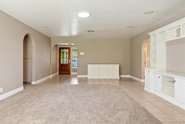 836 Bolen Dr, Paso Robles, CA 93446 - spare room featuring arched walkways, light tile patterned floors, a textured ceiling, and light carpet