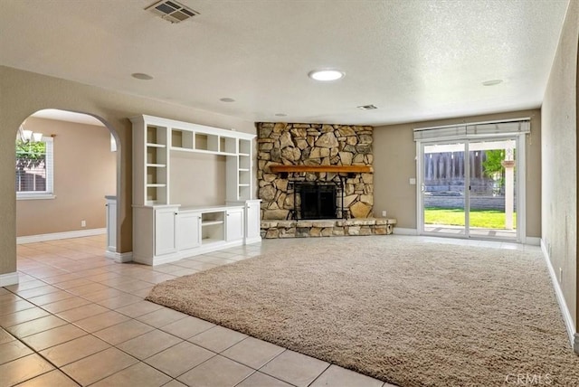 836 Bolen Dr, Paso Robles, CA 93446 - unfurnished living room with arched walkways, a textured ceiling, light tile patterned floors, and a stone fireplace