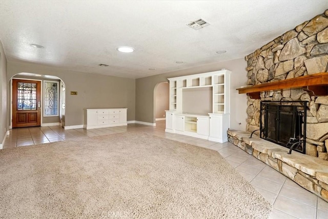 836 Bolen Dr, Paso Robles, CA 93446 - unfurnished living room with arched walkways, tile patterned flooring, a textured ceiling, carpet, and a stone fireplace