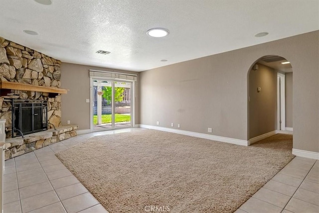 836 Bolen Dr, Paso Robles, CA 93446 - unfurnished living room with light tile patterned flooring, arched walkways, a textured ceiling, and a stone fireplace