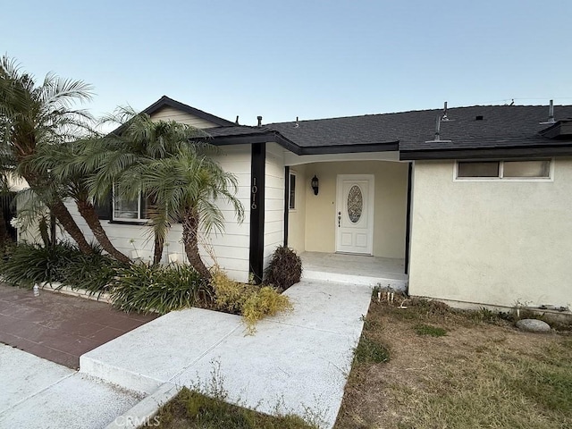 1016 W Teresa St, West Covina, CA 91790 - doorway to property featuring roof with shingles and stucco siding