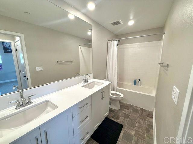 1959 Minimalist Ln, Chula Vista, CA 91915 - bathroom featuring double vanity, shower / bath combo, and stone finish floors
