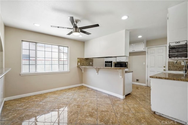 10265 Lev Ave, Arleta, CA 91331 - kitchen featuring a ceiling fan, a peninsula, white cabinetry, dark stone counters, and a kitchen bar