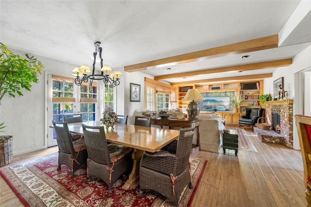 5250 Scott Robertson Rd, Hidden Hills, CA 91302 - dining area with a chandelier, light wood-style flooring, a fireplace, beamed ceiling, and a textured ceiling