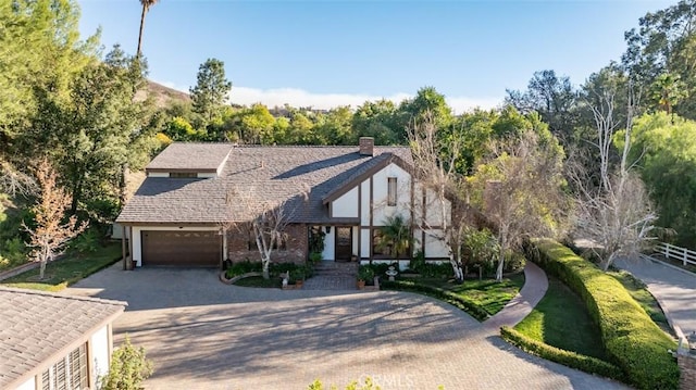 5250 Scott Robertson Rd, Hidden Hills, CA 91302 - tudor-style house with decorative driveway, a garage, a chimney, and brick siding