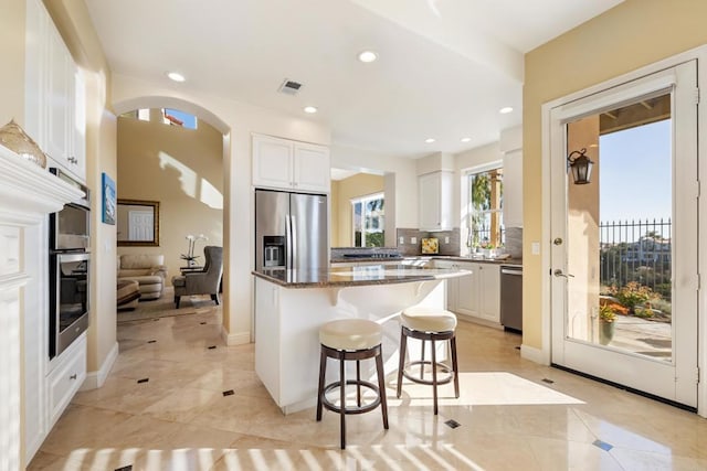 7243 Surfbird Cir, Carlsbad, CA 92011 - kitchen with appliances with stainless steel finishes, a breakfast bar area, a kitchen island, light tile patterned flooring, and white cabinetry