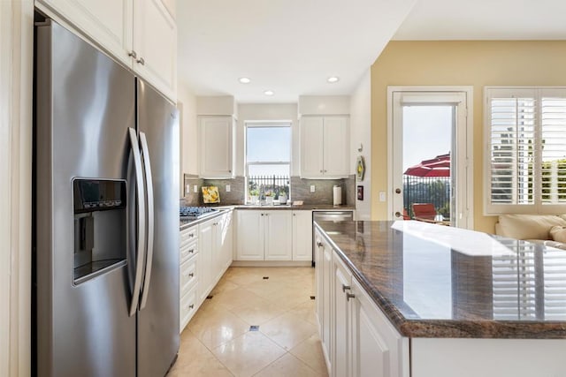 7243 Surfbird Cir, Carlsbad, CA 92011 - kitchen with stainless steel fridge with ice dispenser, tasteful backsplash, white cabinetry, dark stone counters, and light tile patterned flooring