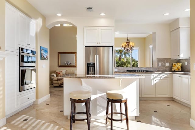 7243 Surfbird Cir, Carlsbad, CA 92011 - kitchen with stainless steel appliances, a kitchen breakfast bar, a kitchen island, tasteful backsplash, and white cabinetry