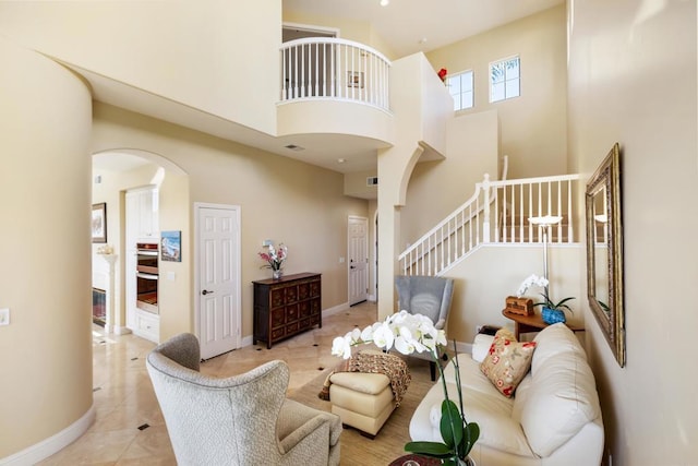 7243 Surfbird Cir, Carlsbad, CA 92011 - living area featuring arched walkways, a high ceiling, tile patterned flooring, and stairway