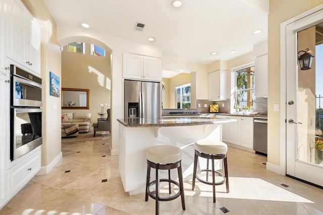 7243 Surfbird Cir, Carlsbad, CA 92011 - kitchen with stainless steel appliances, a breakfast bar area, white cabinetry, backsplash, and recessed lighting
