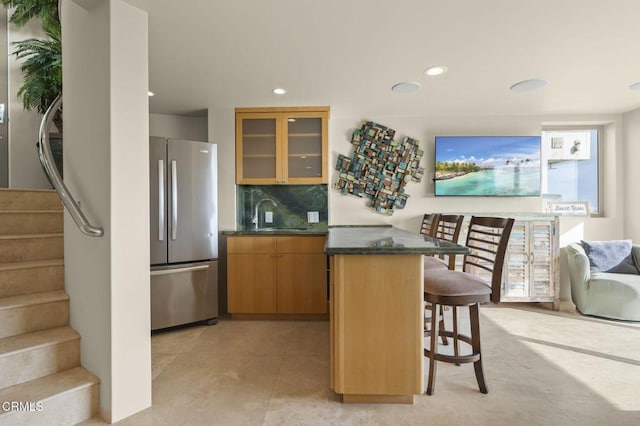 3629 Ocean Dr, Oxnard, CA 93035 - kitchen featuring freestanding refrigerator, a breakfast bar area, glass insert cabinets, backsplash, and recessed lighting