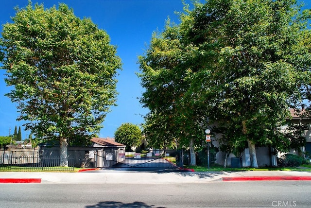 1718 Puente Ave Unit 40, Baldwin Park, CA 91706 - view of asphalt road with a gate, sidewalks, curbs, and street lights