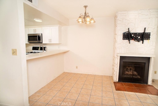 1718 Puente Ave Unit 40, Baldwin Park, CA 91706 - kitchen with stainless steel microwave, white range with gas stovetop, a chandelier, white cabinets, and light tile patterned flooring