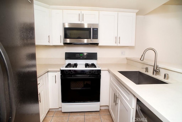 1718 Puente Ave Unit 40, Baldwin Park, CA 91706 - kitchen with stainless steel microwave, gas range oven, freestanding refrigerator, light tile patterned floors, and white cabinetry