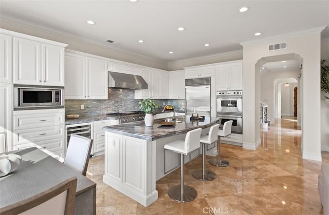 3 Atlantis Cv, Newport Coast, CA 92657 - kitchen featuring built in appliances, ventilation hood, a breakfast bar area, ornamental molding, and decorative backsplash