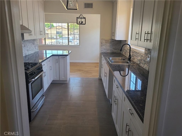 12817 Larwin Rd, Norwalk, CA 90650 - kitchen with stainless steel gas range oven, white cabinets, under cabinet range hood, dark stone counters, and tasteful backsplash