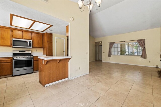37702 Medea Ct, Palmdale, CA 93550 - kitchen with stainless steel appliances, brown cabinets, light tile patterned floors, open floor plan, and tile counters