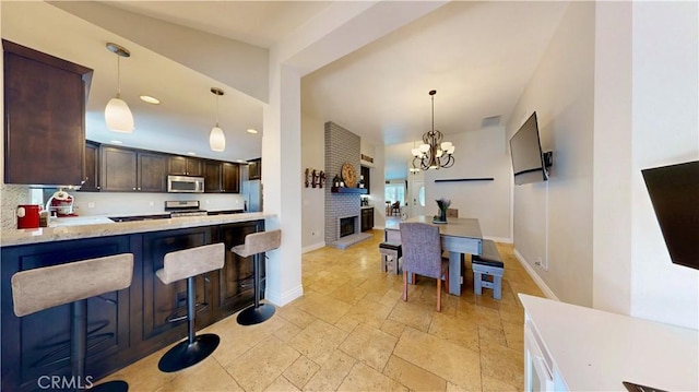 7413 Crimson Dr, Highland, CA 92346 - kitchen featuring appliances with stainless steel finishes, dark brown cabinets, stone tile flooring, pendant lighting, and recessed lighting