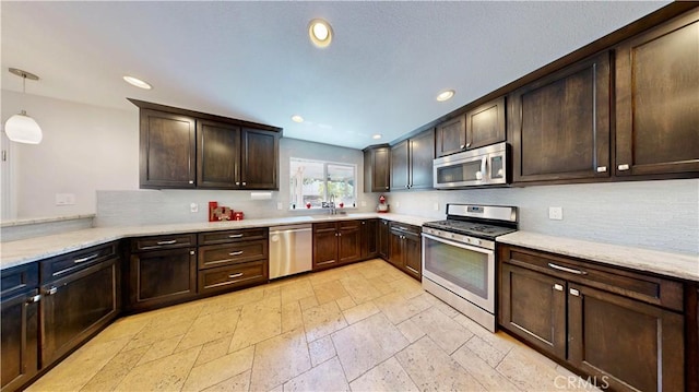 7413 Crimson Dr, Highland, CA 92346 - kitchen featuring appliances with stainless steel finishes, dark brown cabinets, stone tile floors, decorative backsplash, and recessed lighting