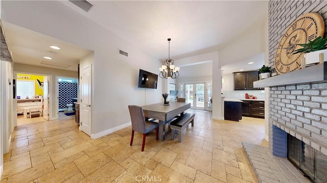7413 Crimson Dr, Highland, CA 92346 - dining room with stone tile floors, a brick fireplace, a chandelier, recessed lighting, and french doors