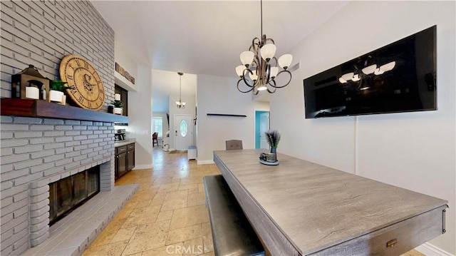 7413 Crimson Dr, Highland, CA 92346 - dining room featuring stone tile flooring, a brick fireplace, and a chandelier