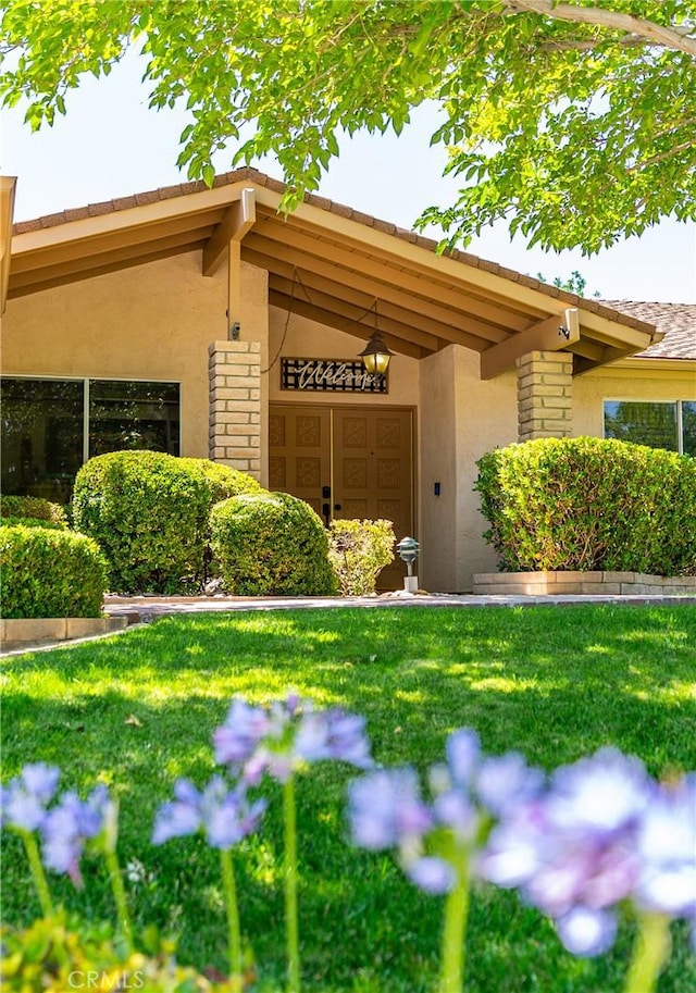 2608 Nice Ct, Lancaster, CA 93536 - view of exterior entry featuring stucco siding, a lawn, and stone siding