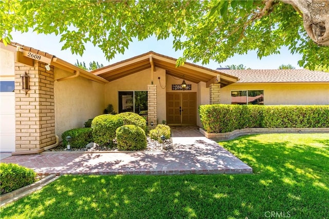 2608 Nice Ct, Lancaster, CA 93536 - property entrance featuring stucco siding, a lawn, and a garage