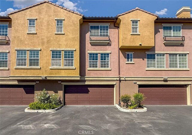 374 E Hilltop Way, Thousand Oaks, CA 91362 - rear view of property featuring stucco siding, an attached garage, driveway, and a tile roof