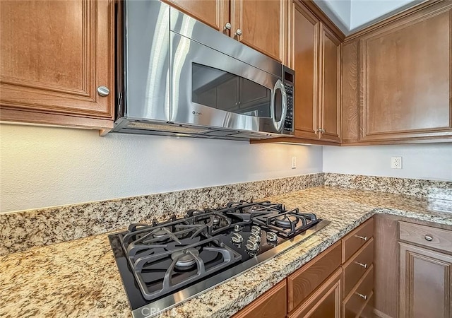 374 E Hilltop Way, Thousand Oaks, CA 91362 - kitchen featuring stainless steel microwave, black gas cooktop, brown cabinetry, and light stone countertops