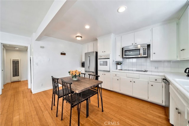 217 E Balboa Blvd, Newport Beach, CA 92661 - kitchen featuring stainless steel appliances, a heating unit, light countertops, decorative backsplash, and white cabinetry