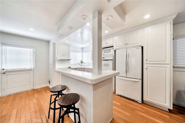 217 E Balboa Blvd, Newport Beach, CA 92661 - kitchen with white appliances, tile countertops, a center island, light wood-style floors, and white cabinets