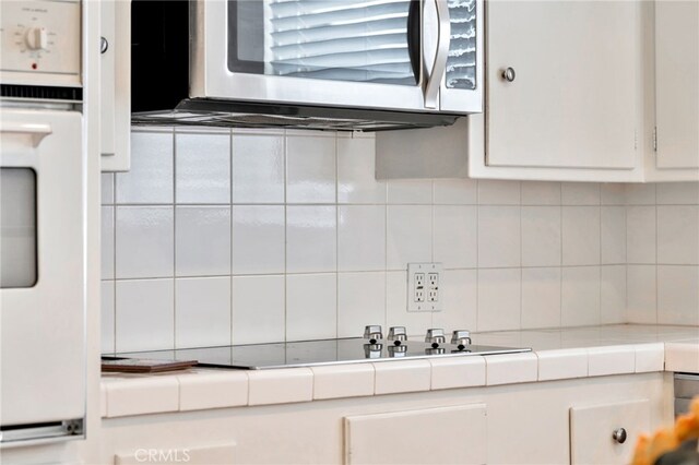 217 E Balboa Blvd, Newport Beach, CA 92661 - kitchen with stainless steel microwave, tile countertops, white cabinets, decorative backsplash, and oven