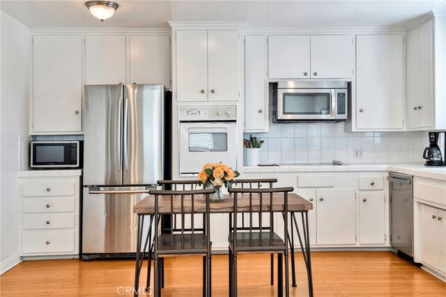 217 E Balboa Blvd, Newport Beach, CA 92661 - kitchen featuring stainless steel appliances, tile countertops, backsplash, and white cabinets