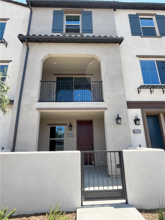 12247 Elliott Ave Unit F, El Monte, CA 91732 - view of front of home featuring a fenced front yard, a balcony, stucco siding, and a gate